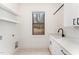 Well-lit laundry room with window, white cabinets, stone countertop, black fixtures and open shelving at 148 Evington Dr, Pittsboro, NC 27312
