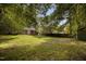 Spacious backyard with lush green grass, mature trees, a wooden fence, and a cozy fire pit area at 1512 Maybrook Dr, Raleigh, NC 27610