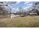 Rear view of the home, highlighting its setting among trees and space for parking at 161 Kerr Lake Club Dr, Henderson, NC 27537