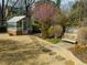 Charming backyard featuring a greenhouse, stepping stone pathway, mature landscaping, and bench at 201 W Park Dr, Raleigh, NC 27605
