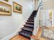 Traditional staircase with carpet runner, white railings, and adjacent hardwood floors at 201 W Park Dr, Raleigh, NC 27605