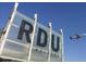 RDU airport sign in front of a clear blue sky with an airplane taking off in the distance at 2013 Trident Maple Ln, Chapel Hill, NC 27517