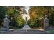 Scenic driveway entrance, featuring stately stone pillars, and a distant tower through lush foliage at 2021 Trident Maple Ln, Chapel Hill, NC 27517