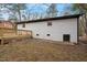 View of the rear exterior of home featuring a light grey brick, wooden deck and walkout basement at 2607 Nation Ave, Durham, NC 27707