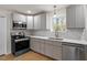 Bright kitchen featuring stainless steel appliances, grey cabinetry, and tiled backsplash at 2607 Nation Ave, Durham, NC 27707