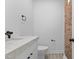 Modern half bathroom featuring a stone vanity top, sleek fixtures, and eye-catching brick accent wall at 405 N Hyde Park Ave, Durham, NC 27703