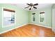 Bedroom with hardwood floors, light green walls, base trim, and three bright windows at 532 Front Ridge Dr, Cary, NC 27519