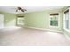 Spacious bedroom with a door, neutral carpet, and light green walls illuminated by two large windows at 532 Front Ridge Dr, Cary, NC 27519