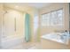 Bright bathroom featuring double sink vanity, tiled shower and tub with grab bar, and window at 10 Marchmont Ct, Durham, NC 27705