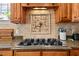 Close-up of a gas stovetop with granite countertops and decorative tile backsplash at 1328 Wakefield Farm Rd, Zebulon, NC 27597