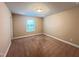 Simple bedroom with neutral walls and carpet, featuring a window, ceiling light and door at 1546 Tinos Overlook Way, Apex, NC 27502