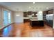 Spacious kitchen with dark wood cabinets, center island, stainless steel appliances, and hardwood floors at 1546 Tinos Overlook Way, Apex, NC 27502