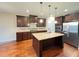 Spacious kitchen with dark wood cabinets, center island, stainless steel appliances, and hardwood floors at 1546 Tinos Overlook Way, Apex, NC 27502