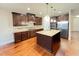 Spacious kitchen with dark wood cabinets, center island, stainless steel appliances, and hardwood floors at 1546 Tinos Overlook Way, Apex, NC 27502