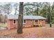 View of the back exterior of a brick house with a wooden deck, small porch, and wooded yard at 2116 Nc Highway 751, Apex, NC 27523