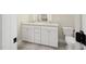 Bathroom featuring a double vanity sink with white cabinets, plus a toilet and decorative floor tiles at 2410 Carpenter Pond Rd, Raleigh, NC 27613