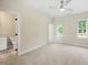 Bedroom showcasing a ceiling fan and two large windows with forest views, with an open door to the bathroom at 2410 Carpenter Pond Rd, Raleigh, NC 27613
