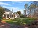 Large backyard with green lawn, mature trees, and a brick home featuring solar panels and a covered patio at 3605 Camp Mangum Wynd, Raleigh, NC 27612