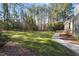 A spacious backyard featuring a well-maintained lawn with a stone pathway, lush greenery, and mature trees at 3605 Camp Mangum Wynd, Raleigh, NC 27612