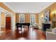 Spacious living room with hardwood floors, fireplace, piano, and bright, natural light from large windows at 3605 Camp Mangum Wynd, Raleigh, NC 27612