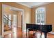 Living room highlighting hardwood floors, piano, and large windows providing ample natural light with a staircase in view at 3605 Camp Mangum Wynd, Raleigh, NC 27612