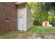 Exterior side of a storage building with a door and a peek at another building in the tree filled backyard at 6025 Spring Valley Dr, Raleigh, NC 27616