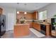 Well-lit kitchen with wood cabinets, granite countertops, stainless steel appliances, and a functional center island at 610 Chalcedony Ct, Durham, NC 27703