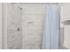 Modern shower featuring stylish marble tiling, a built-in niche, and a shower curtain at 1012 Holloway St, Durham, NC 27701
