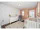 Charming Bedroom with soft colors, patterned wallpaper, crib and dresser creates a warm and inviting space for baby at 1127 Sweet Cream Ct, Durham, NC 27703