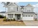 Inviting two-story house boasts a gray facade, a covered porch with chairs, and a two-car garage at 1829 Knights Crest Way, Wake Forest, NC 27587