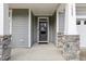 Inviting front porch featuring stone accents, a dark-colored front door, and a covered entryway at 1829 Knights Crest Way, Wake Forest, NC 27587