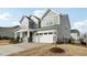Side view of a two-story home with a large two-car garage and well-maintained landscaping at 1829 Knights Crest Way, Wake Forest, NC 27587