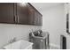 Well-equipped laundry room with modern washer, dryer, sink, and overhead cabinets for storage at 1829 Knights Crest Way, Wake Forest, NC 27587