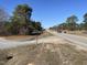 Road view featuring mature trees, passing cars, and glimpses of the surrounding landscape at 2113 Nc 55, Coats, NC 27521