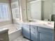 Bathroom featuring a soaking tub under frosted window, double vanity and marble tile floor at 2114 Stoney Spring Dr, Raleigh, NC 27610