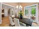 Bright dining room with wooden table, chandelier, and access to an outdoor seating area with a wooded view at 216 Copper Beech Ct, Chapel Hill, NC 27517