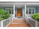 Inviting front entrance with a wooden door, white columns, and lush greenery enhancing its curb appeal at 216 Copper Beech Ct, Chapel Hill, NC 27517