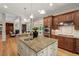 Open-concept kitchen flows into a well-lit living area featuring a functional island, stainless appliances, and granite countertops at 216 Copper Beech Ct, Chapel Hill, NC 27517