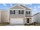 Two-story home featuring gray siding, brick accents, a white garage door, and black shutters at 258 Palm Dr, Sanford, NC 27332