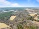 Aerial view of a farm-like community surrounded by dense forest and a large, open field at 4051 Silk Hope Gum Springs Rd, Pittsboro, NC 27312