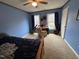 Blue bedroom featuring a ceiling fan, tan carpet, and a desk by the windows at 4051 Silk Hope Gum Springs Rd, Pittsboro, NC 27312