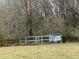 Dilapidated chicken coop on a grassy field surrounded by trees, a fence, and some brush at 4051 Silk Hope Gum Springs Rd, Pittsboro, NC 27312