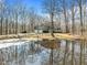 View of the home from across the pond, with a two-car garage and mature trees. Reflection on the water at 4051 Silk Hope Gum Springs Rd, Pittsboro, NC 27312