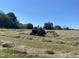 View of open field with tractor and freshly cut hay at 4051 Silk Hope Gum Springs Rd, Pittsboro, NC 27312