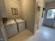 Bright laundry room features a white washer and dryer, neutral walls, and access to the back porch at 4051 Silk Hope Gum Springs Rd, Pittsboro, NC 27312
