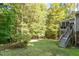 Backyard featuring a well-maintained lawn, mature trees, and a raised deck with stairs, perfect for outdoor entertaining at 407 Crickentree Dr, Cary, NC 27518