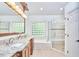 Bathroom with double sink vanity, soaking tub, glass door shower, and brick glass window at 407 Crickentree Dr, Cary, NC 27518