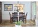 Formal dining room featuring hardwood floors, white walls, large chandelier, dining table, and view to kitchen at 407 Crickentree Dr, Cary, NC 27518