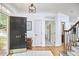 Bright foyer with hardwood floors, staircase, black door with gold numbers, rug, and view to dining area at 407 Crickentree Dr, Cary, NC 27518