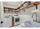 Bright laundry room featuring modern washer and dryer, wooden shelves, and sink at 407 Crickentree Dr, Cary, NC 27518